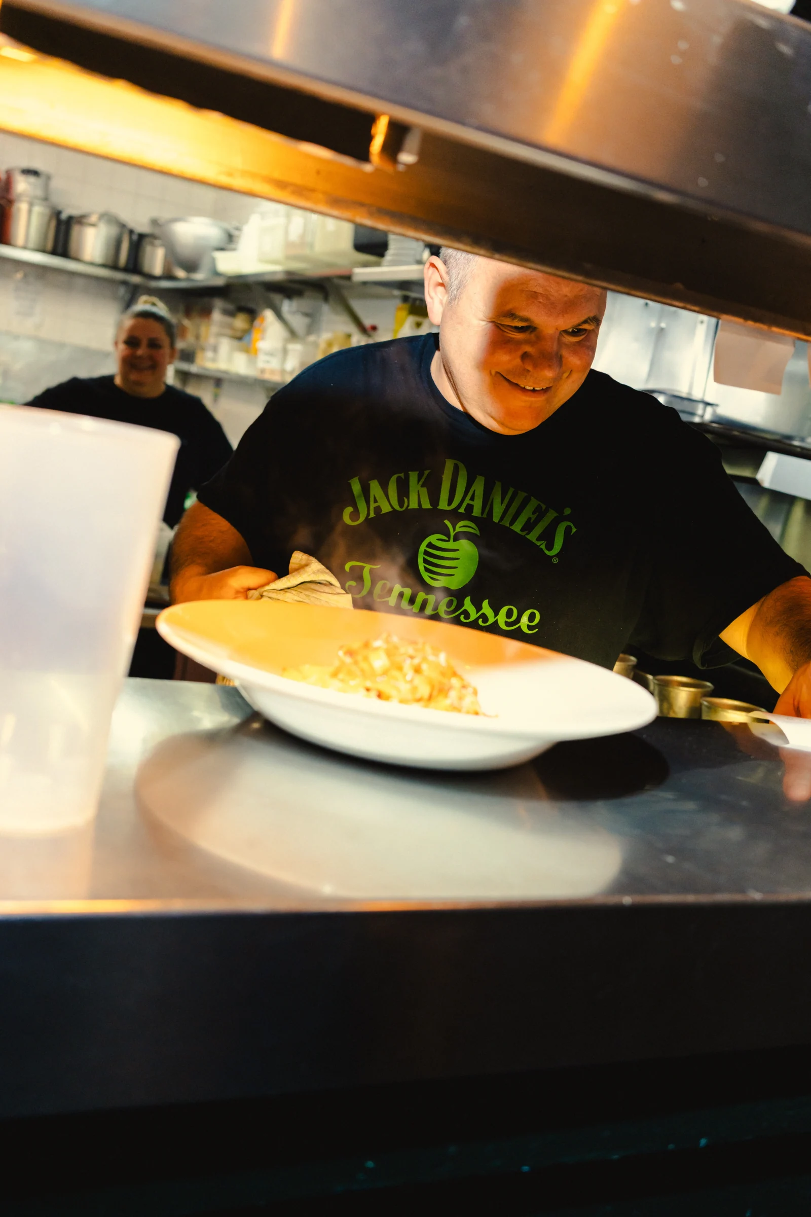 Chef passing a plated dish through the kitchen hatch
