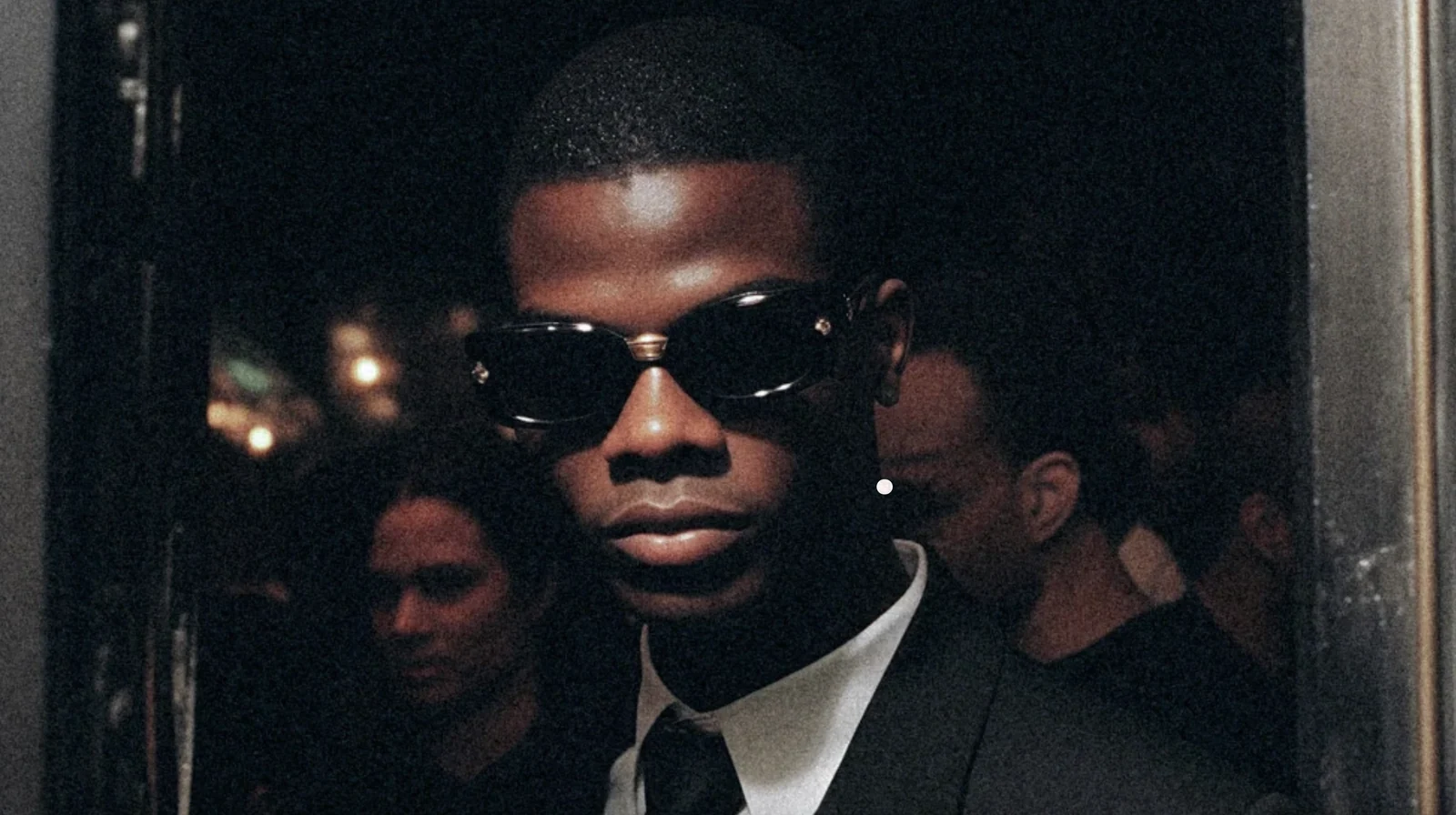 Guest wearing dark sunglasses and a suit at an evening event