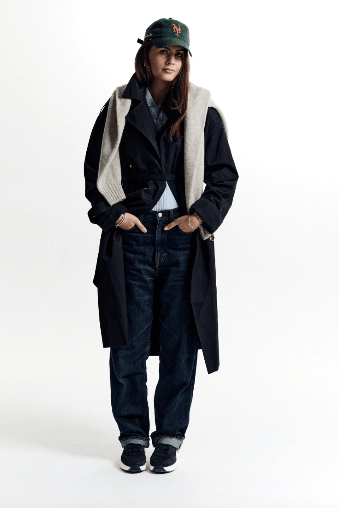Model wearing a long dark coat and green cap