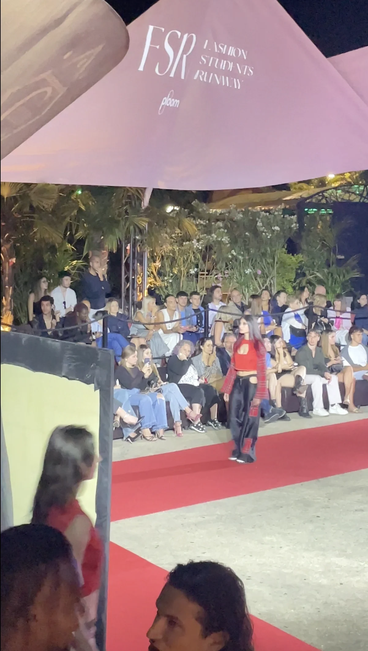 Model walking the red runway in front of the seated audience