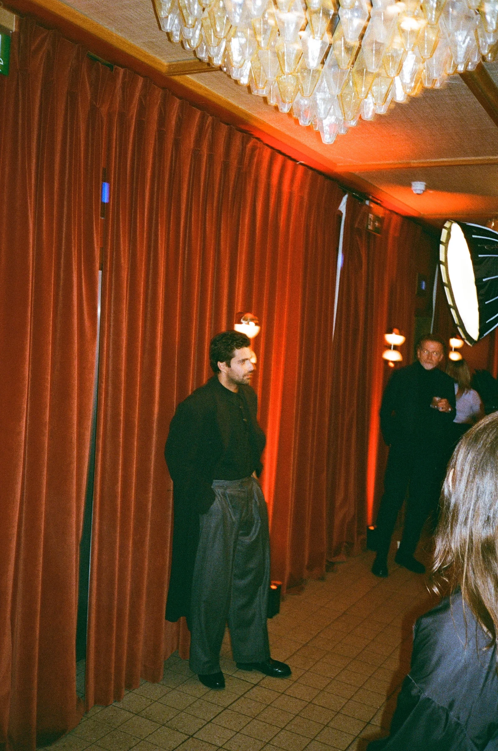 Guest standing beside red velvet curtains at a London Film Festival event
