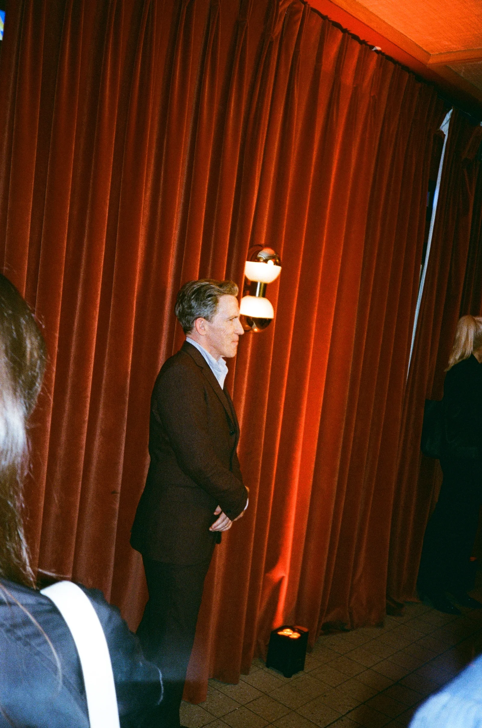 Guest photographed beside red velvet curtains