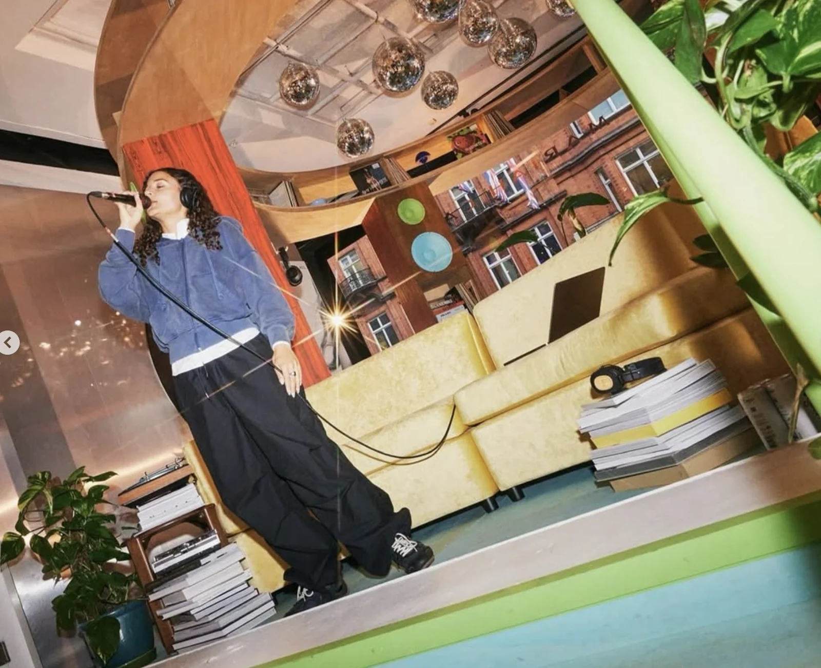 Singer in a blue shirt performing beside plants and vinyl displays at Selfridges