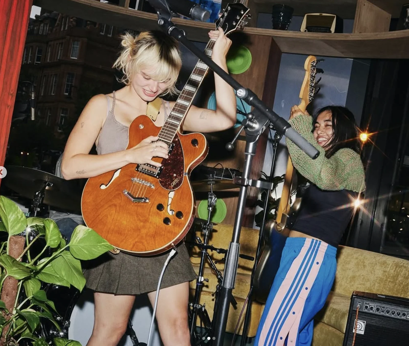 Guitarist playing beside a microphone and indoor plants